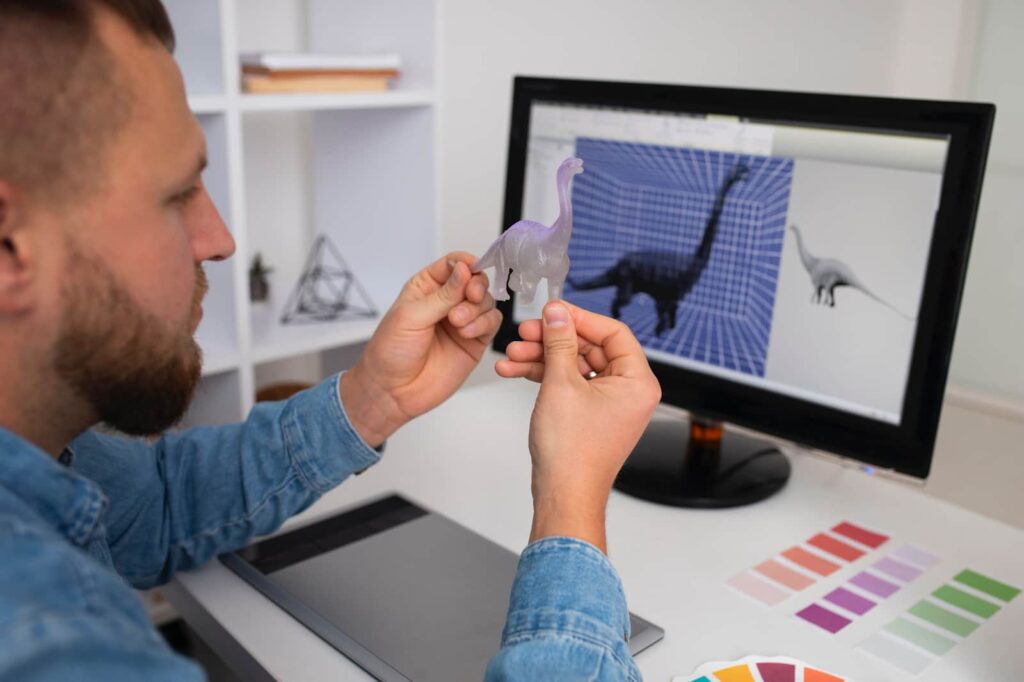 A man looks at a dinosaur model next to his computer